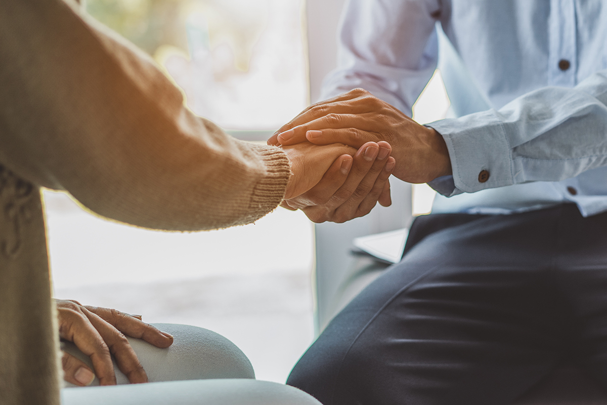 one person holding another person's hand in a supportive gesture